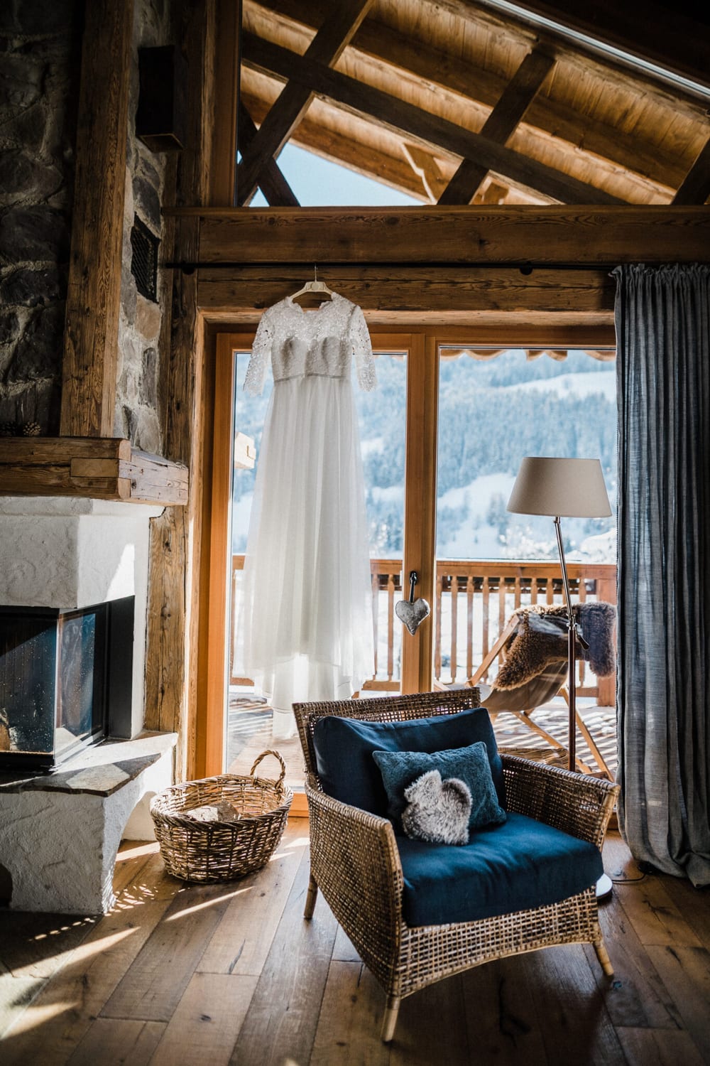 Brautkleid h&auml;ngt am Fenster der Kuschelh&uuml;tte mit Blick auf die verschneiten Berge