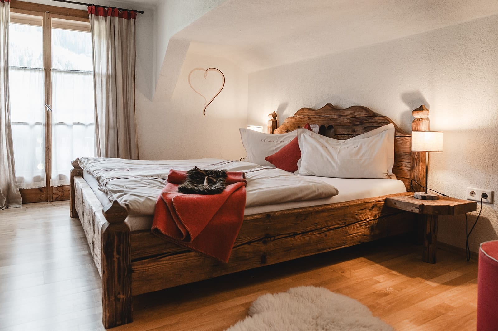 Doppelbett aus Massivholz mit Esel-Plüsch und Wandherz im zweiten Schlafzimmer der Eseltraum